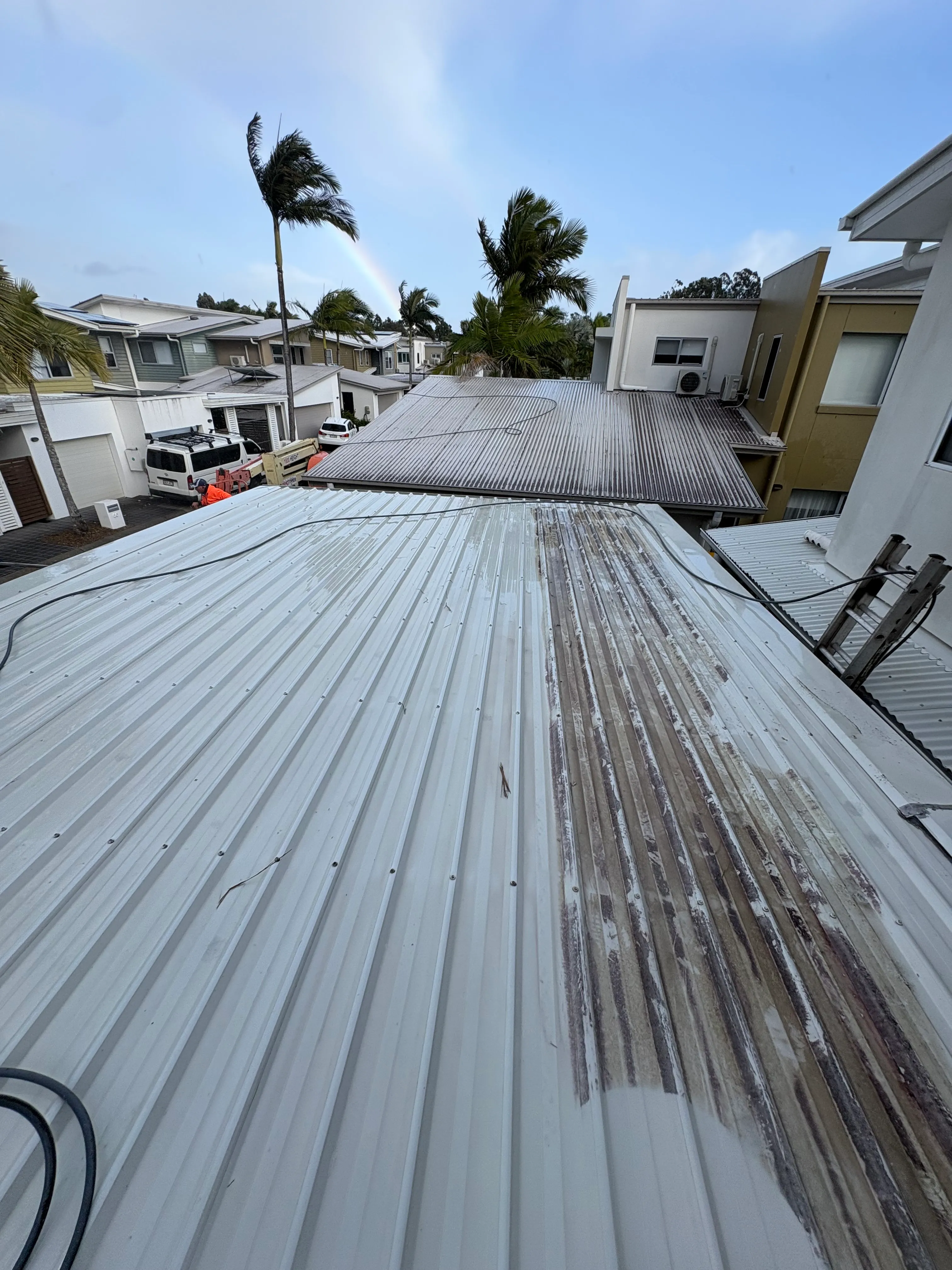 Metal roof cleaning in progress with cleaned and weathered sections visible